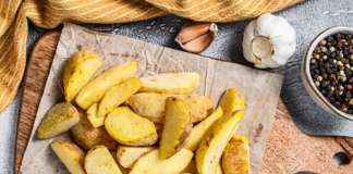 Frozen potato wedges on a cutting board. Recipe for French Fries. White background. Top view