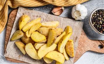 Frozen potato wedges on a cutting board. Recipe for French Fries. White background. Top view